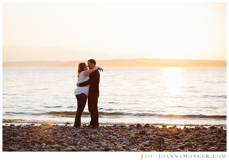 engaged couple kissing at Carkeek Park in Seattle on beach at sunset